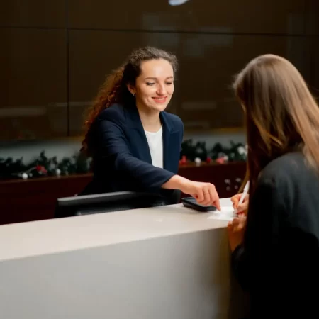 a smiling receptionist helping a guest to fill out a registration form at the hotel