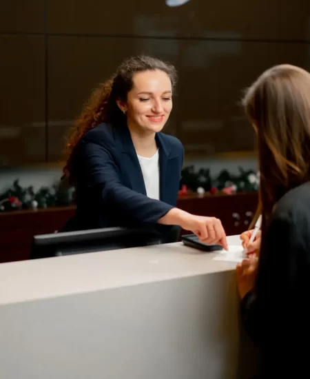 a smiling receptionist helping a guest to fill out a registration form at the hotel